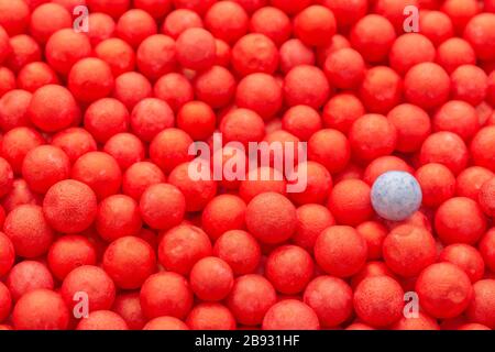 Farbige kleine rote und blaue Polystyrolkugeln. Konzeptionell für Covid-19 Selbstisolation, Krankheitsträger, infizierte Person, isoliert, in der Menge verloren Stockfoto