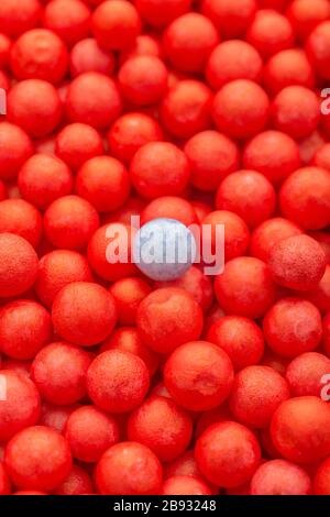 Farbige kleine rote und blaue Polystyrolkugeln. Konzeptionell für Covid-19 Selbstisolation, Krankheitsträger, infizierte Person, isoliert, in der Menge verloren. Stockfoto