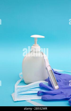 Handgel, Thermometer, medizinische Handschuhe und Gesichtsschutzmaske auf blauem Hintergrund. Schutz von Coronavirus, Covid-19-Konzept. Stockfoto