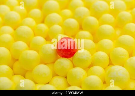 Gelbe und rote kleine Polystyrolkugeln. Konzeptionell für Covid-19 Selbstisolation, Krankheitsträger, infizierte Person, isoliert, in der Menge verloren. Stockfoto