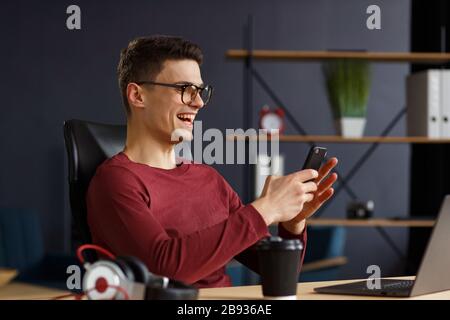 Junger Mann mit Smartphone und Lächeln. Glücklicher Geschäftsmann Stockfoto