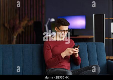 Junger Freiberufler mit Smartphone und Lächeln. Glücklicher Mann mit m Stockfoto