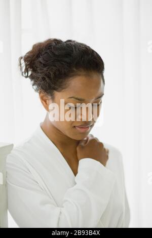 Junge Frau, die während des Tragens einer weißen Robe nach unten blickt. Stockfoto