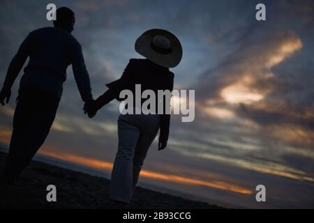 Mitte nach paar Hände halten und entlang einem abgelegenen Strand bei Sonnenuntergang. Stockfoto