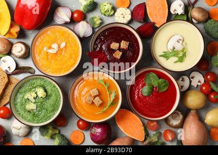 Gemüsesuppen und Zutaten auf grauem Hintergrund, Draufsicht Stockfoto