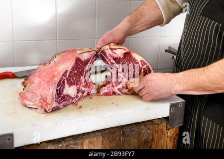 Metzger zeigt Stücke roher gerippter Augenschinkfleisch auf Schneidebrett Stockfoto