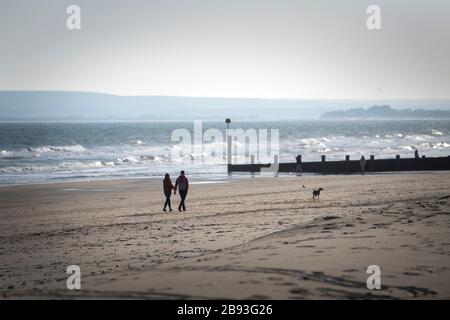 Spaziergänger am Strand von Bournemouth in Dorset, nachdem Premierminister Boris Johnson gesagt hat, dass die Regierung bereit ist, härtere Beschränkungen zu verhängen, um die Ausbreitung des Coronavirus einzudämmen, wenn die Menschen nicht den Leitlinien für soziale Distanzierungen folgen. Stockfoto