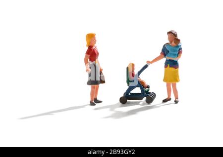 Miniatur-Szene einer Frau mit Zwillingsbabys, eine auf dem Arm und eine in einem Kinderwagen, die aufgehört, mit einer weiblichen Freundin über Weiß mit Schatten und Co zu chatten Stockfoto