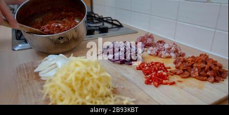 Pizza Tomatensauce wird neben einer Vielzahl von Pizza-Belägen gezeigt, darunter Käse, Fleisch und etwas VEG. Stockfoto