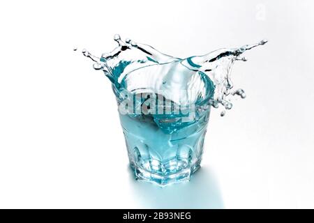 Blaues Wasser spritzt in transparentem Glas. Erfrischendes Getränk. Stockfoto