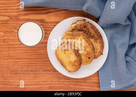 Französischer Toast - Przenice - Brotscheiben, die in geschlagenen Eiern und Milch getränkt und gebraten wurden, mit einem Glas Joghurt auf einem Holztisch. Eggy Brot, Bombay Toast Stockfoto