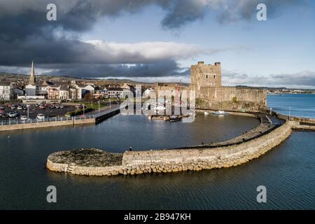 Mittelalterlichen normannischen Burg, Hafen mit Bootsrampe und Wellenbrecher in Carrickfergus bei Belfast, Nordirland, Großbritannien. Luftansicht bei Sonnenuntergang Stockfoto