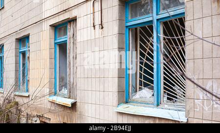 Alte zerbrochene Fenster mit Metallstäben eines verlassenen Krankenhausgebäudes. Stockfoto