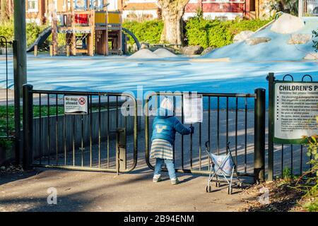 Myatt's Field Park, Camberwell, London, Großbritannien. März 2020. Ein kleines Mädchen steht neben einem Schild mit der Aufschrift "Spielbereich geschlossen" und blickt auf den geschlossenen Spielplatz. Lambeth Council hat alle Sportanlagen und Spielplätze geschlossen, da sie nicht über die Mittel verfügen, die Anlagen ausreichend zu sanieren. Kredit: Tom Leighton/Alamy Live News Stockfoto