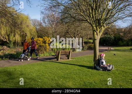 Nach einem Wochenende, an dem viele Briten London für Ferienorte und Küstenschönheiten verlassen und in die Parks der Hauptstadt drängen, erwägt die britische Regierung weitere Einschränkungen der Bewegung an öffentlichen Orten, um während der Pandemie von Coronavirus soziale Distanzierungen zu unterstützen. Einige öffentliche Grünflächen wurden von ihrer eigenen örtlichen Behörde geschlossen, die meisten, wie der Ruskin Park im Süden Londons, sind jedoch noch offen. Kerry ist ein lokaler Musiker und Sender und sitzt unter einem Baum, der Musikideen für ihren Podcast hört, am 23. März 2020, in London, England. Stockfoto