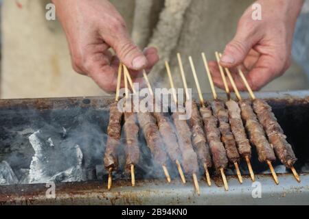 Die Hände des Kochs mit Lamm- und Hammelspießen, die auf Italienisch im Restaurant ARROSTICINI genannt werden Stockfoto