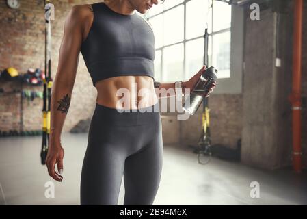 Gesunder Lebensstil. Zugeschnittenes Foto von jungen Sportfrauen in Sportbekleidung, die beim Training im Fitnessstudio eine Flasche Wasser halten. Profisport. TRX-Schulung. Stockfoto