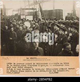 Fotografie Propaganda Ankunft in Lyon eines Konvois von Gefangenen repatriiert Gallia. "Photographie propagande: Arrivée à Lyon d'un convoi de prisonniers rapatriés". LA RELEVE / LYON- UN nouveau convoi de Prisonniers rapatriés au titer / de la relève, vient d'arriver à Lyon, ou un chaleureux accu / euil leur était Réservé. / N.P.M. Ein leur descente du train, les Prisonniers passent devant / le drapeau d'une Légion de la Garde, venue les accueillir. Tirage au gélatino-bromure d'argent. Légende dactylographiée à l'encre noire. En 1943-01-04-1943-01-04. Paris, musée Carnavalet. Stockfoto