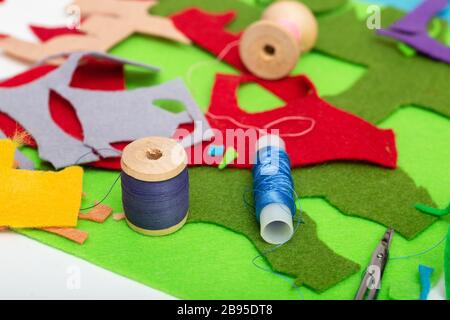 Farbiges Filz, Faden, Nadeln und Scheren auf dem weißen Tisch Stockfoto