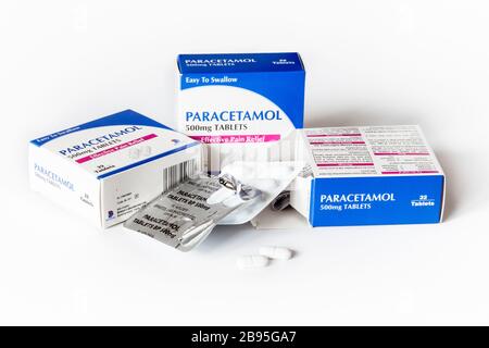 Schachteln mit Paracetamol-Tabletten und Blisterpackungen, zwei Tabletten entfernt, vor einem einfachen Hintergrund Stockfoto