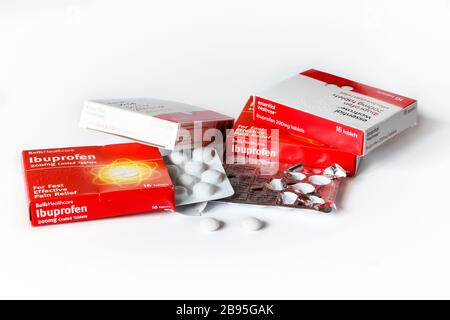 Faltschachteln mit Ibuprofen-Tabletten und Blisterpackungen, aus denen zwei Tabletten entfernt werden, auf weißem Hintergrund Stockfoto