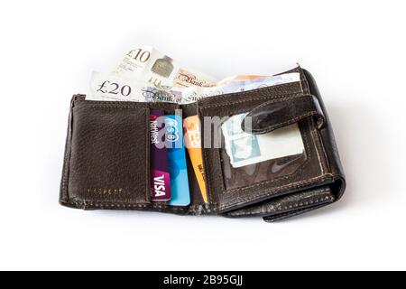 Eine offene, braune Umklapptasche aus Leder mit 10 £und 20 £britischen Banknoten und Kreditkarten Stockfoto