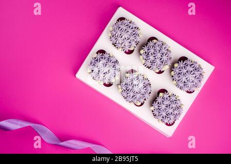 Köstliche schäubkuchen mit Quark in Form von Blumen auf pinkfarbenem Hintergrund. Weiße Cupcake-Verpackung. Stockfoto