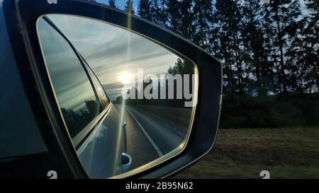 Spiegelung der Autobahn in einem Autospiegel. Getöntes Foto. Road travel concept.Driving Auto in Sunset.Beauty am Himmel auf Reise in der Nacht.Reflexion von Stockfoto