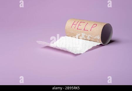 Leere toilettenpapierrolle auf violettem Hintergrund. Hilfe-Wort auf einem Papierrohr geschrieben. Kein konzept für toilettenpapier mehr. Stockfoto