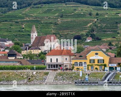 SPITZ, ÖSTERREICH - 13. JULI 2019: Blick auf die terrassenförmig angelegten Weingärten über der Stadt und der Fährstation an der Donau Stockfoto