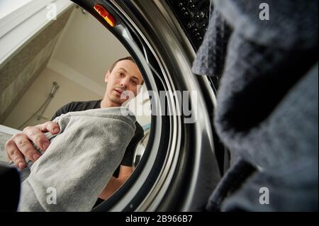 Mann lädt Waschmacheransicht von innen Stockfoto