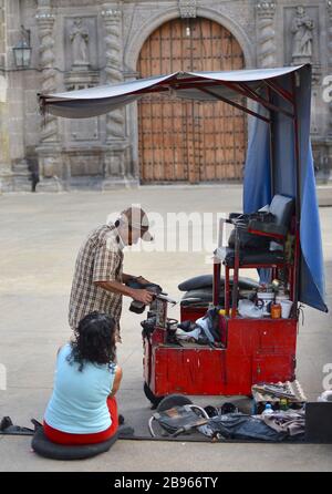 Ein Mann glänzt mit den Schuhen einer Frau von einem Stand vor dem Templo de San Francisco de Asis. Stockfoto