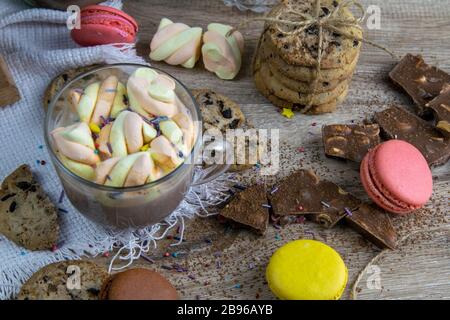 Kakao mit Marshmallows und Schokoladenofen, Muffins und Schokoladenscheiben stehen auf Holztisch Stockfoto