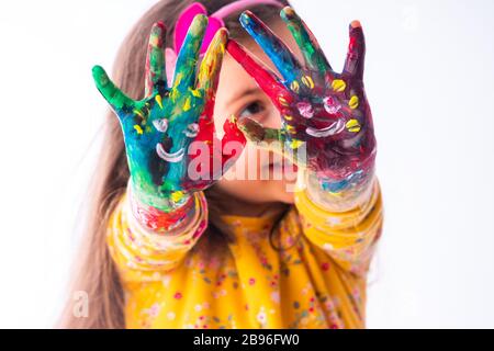 Kleines glückliches Studenten-Mädchen mit gemalten Händen - Kinder- und Zeichenkonzept, Bildung und Kunst Stockfoto