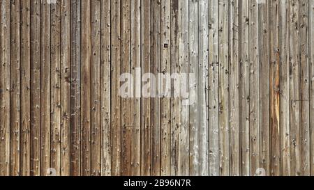 Holzholzwand einer alten Scheune. Schöne verwitterte vertikale Bohlen Stockfoto