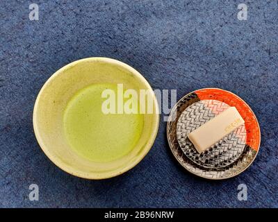 Süß und Tasse mit Matcha auf dem blauen Tisch Stockfoto