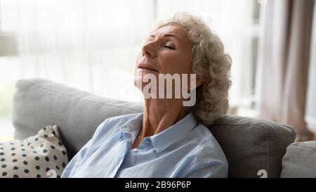 Reife Frau, die sich zu Hause auf der Couch entspannt Stockfoto