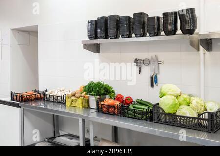 Frisches buntes Gemüse und Obst in der Küche aus silberfarbenem Stahl. Arbeitsfläche und Küchenausstattung in der professionellen Küche. Kochen mit Vorbereitung Stockfoto