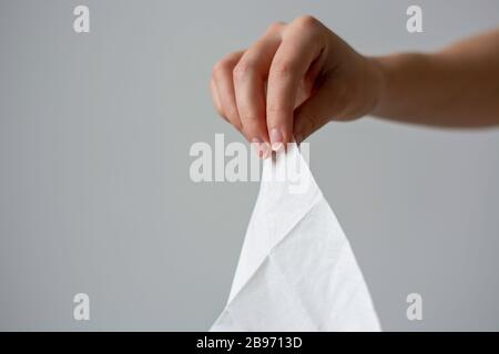 Eine weibliche Hand, die ein weißes, sauberes Einweg-Seidenpapier-Taschentuch hält Stockfoto