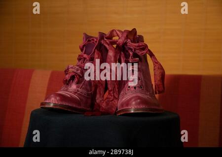 Rote Stiefel mit Seidenspangen und orangefarbenem Streifenhintergrund Stockfoto