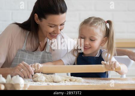 Lächelnde Mutter und Tochter machen zusammen Teig Stockfoto