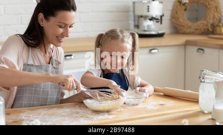 Glückliche Mutter und Tochter bereiten Kuchen in der Küche vor Stockfoto