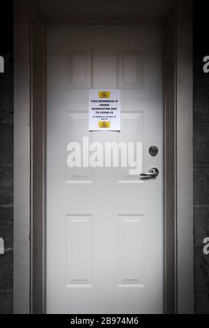 Eine selbstisolierende Residenz mit einem Quarantäneschild an der Vordertür, das vor dem Covid-19-Virus warnt. Stockfoto