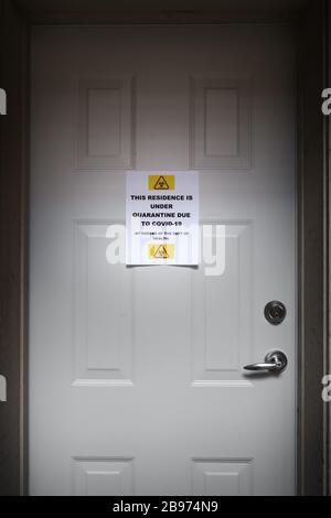 Eine selbstisolierende Residenz mit einem Quarantäneschild an der Vordertür, das vor dem Covid-19-Virus warnt. Stockfoto