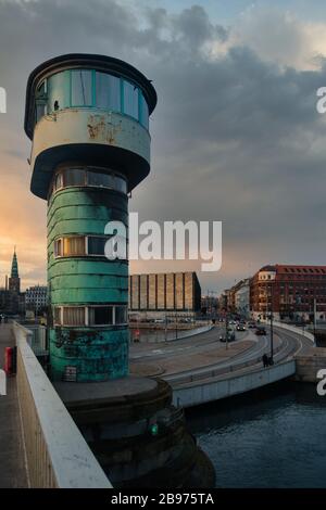 Historischer Brückturm mit dramatischem Himmel und Sonnenuntergang in Kopenhagen, Dänemark. Stadtbild im Hintergrund, Sonne reflektiert in Fenstern. Stockfoto