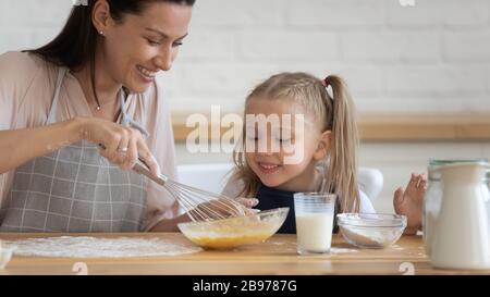 Fröhliche Mutter und Tochter, die Pfannkuchen zusammen kochen Stockfoto