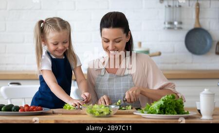 Glückliches kleines Mädchen hilft Mama beim Kochen in der Küche Stockfoto