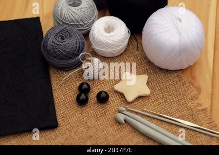 Häkelhaken und Kugeln aus Baumwollfaden auf einem Holztisch, Kopierraum. Stockfoto