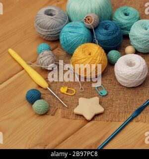 Gelbe und blaue Häkelhaken und Kugeln aus Baumwollfaden auf einem Holztisch, Kopierraum. Stockfoto