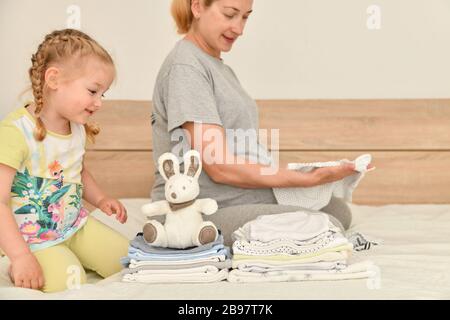 Mutter und Tochter bereiten Kleidung für einen neugeborenen Jungen vor Stockfoto